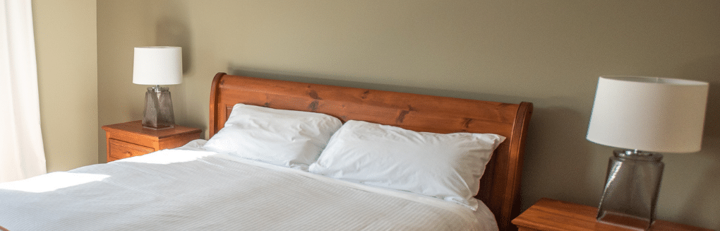 A nicely made bed with lamps on each side.