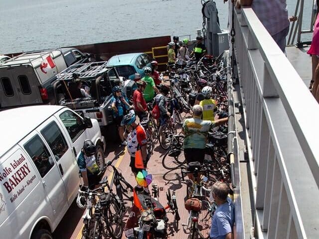 A group of cyclists waiting beside a white van on the Wolfe Island Ferry.