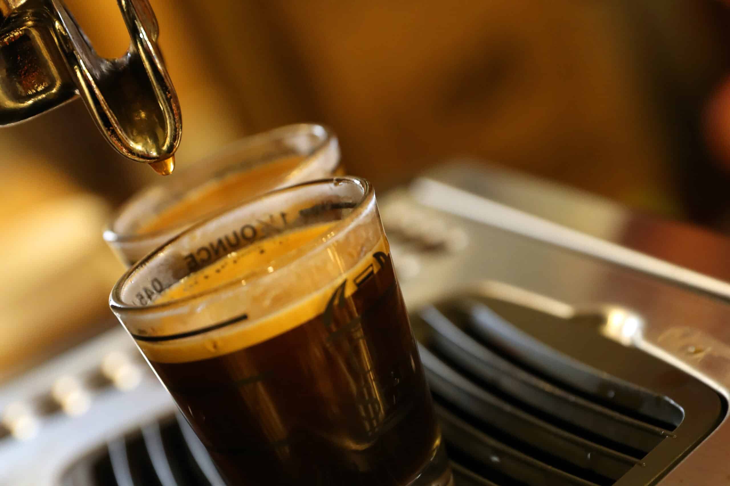A cup of smooth and creamy espresso is poured from a machine.