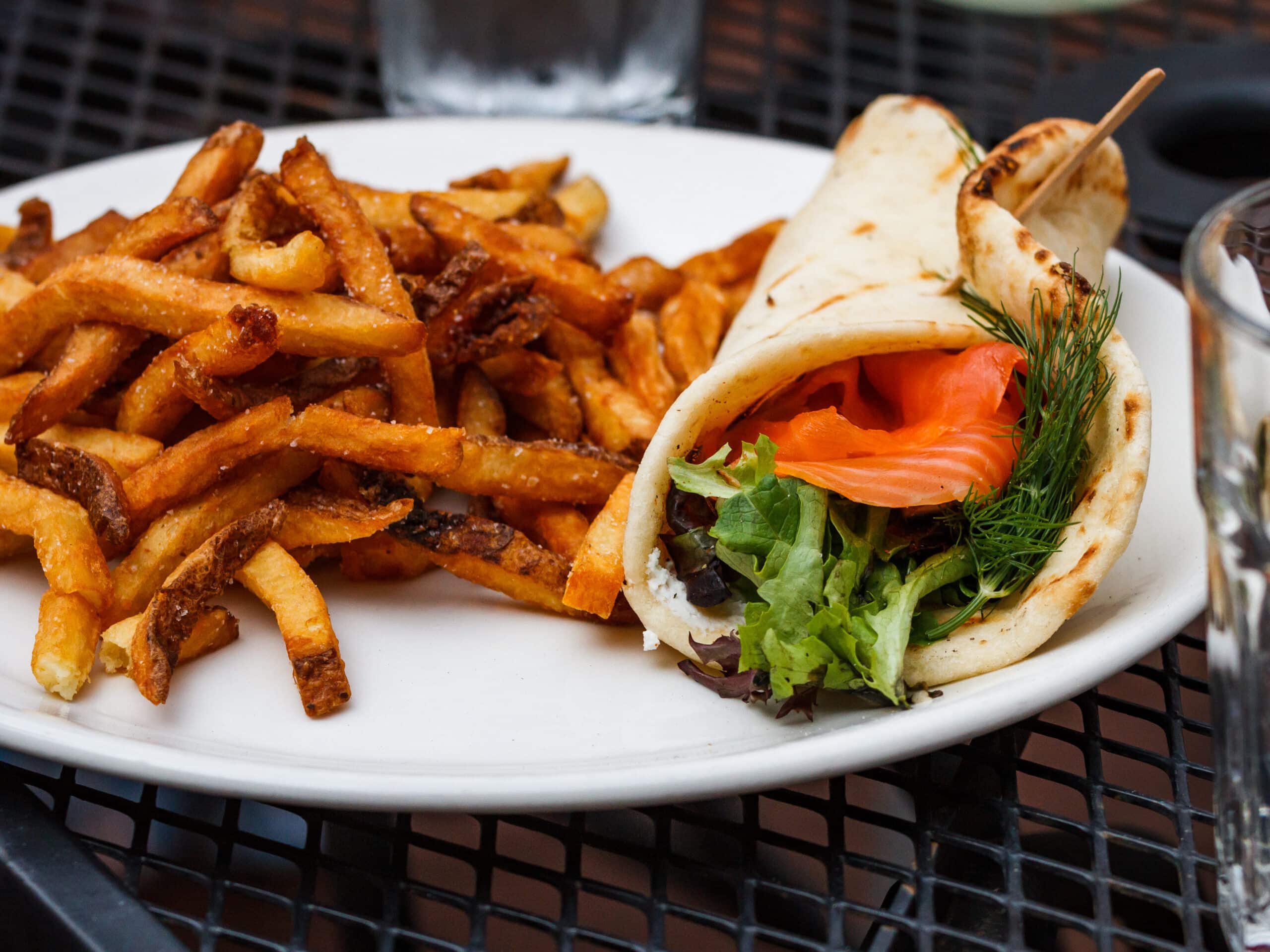 A plate with a savoury chicken wrap and spicy french fries